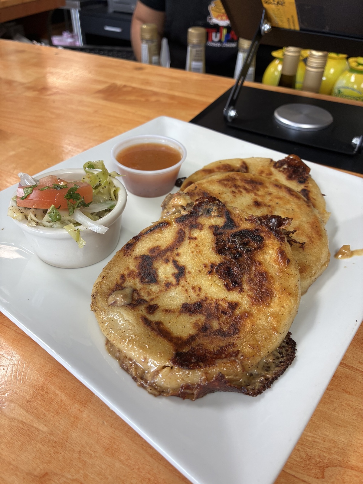 Two handmade pupusas with curtido and salsa roja