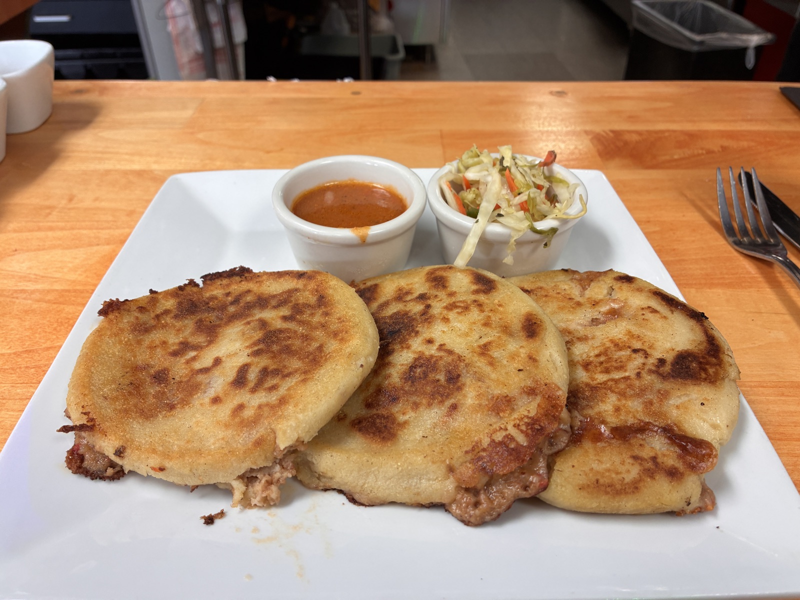 Three golden pupusas with curtido